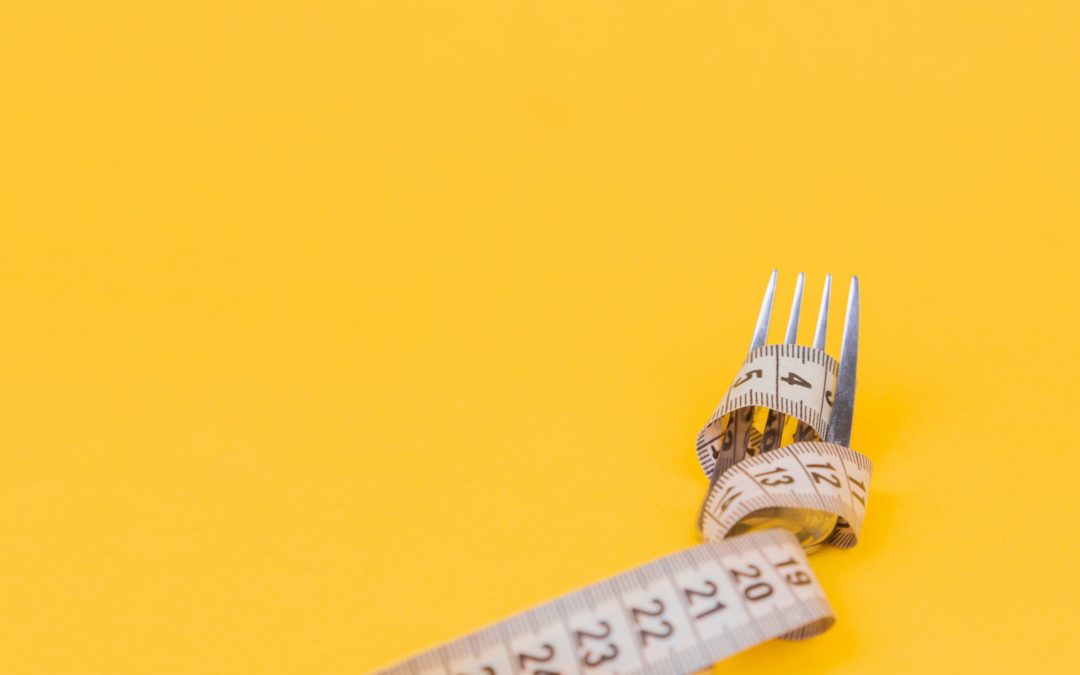 yellow background. Metal fork with a measuring tape wrapped around it